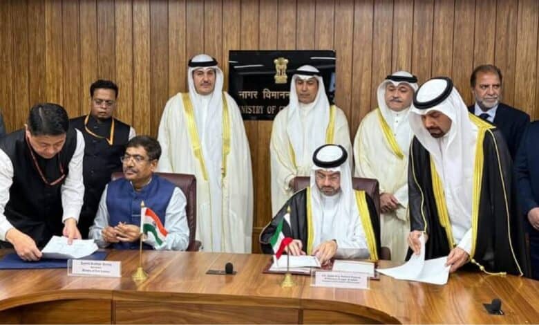 Officials from India and Kuwait sign a bilateral air services agreement in New Delhi, seated at a wooden conference table with national flags and nameplates.