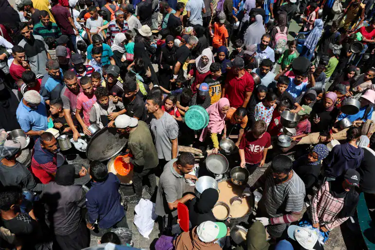 A crowded scene of Palestinians receiving food from a charity kitchen in Nuseirat, Gaza, amid a hunger crisis, July 20, 2025.