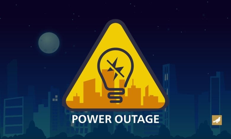 Illustration of a power outage warning, featuring a yellow triangular caution sign with a broken light bulb symbol in front of a city skyline at night.