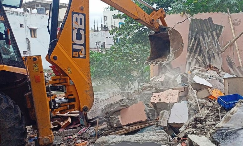 The image shows HYDRAa officials demolishing illegal structures on a nala between Pariki Cheruvu and Kukatpally in Medchal-Malkajgiri district on Monday, August 18, 2025.