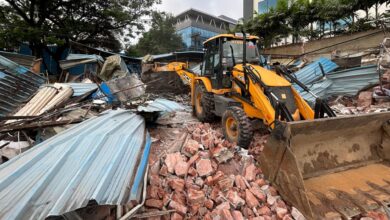The image shows HYDRAA officials demolishing illegal encroachments from government land in Madhapur on Wednesday, August 20.