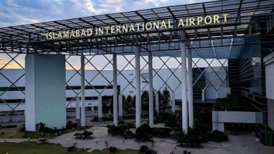 Front view of Islamabad International Airport with its modern glass-and-steel structure and illuminated signage at the entrance.