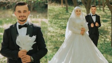 Elegant groom in black tuxedo holding a white bouquet outdoors.