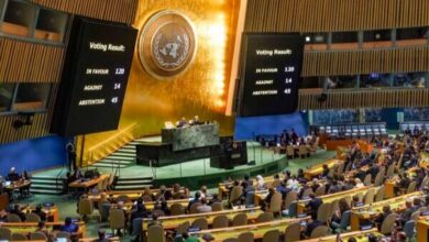 United Nations General Assembly hall showing voting results displayed on screens.