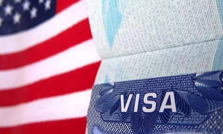 Close-up of a US visa page in a passport with the American flag in the background..