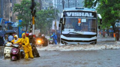 Commuters make way through a waterlogged road amid rainfall in Palghar in Maharashtra on Tuesday. (PTI Photo)