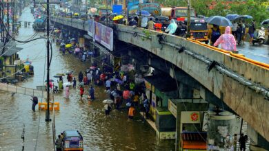 Commuters make way through a waterlogged road amid rainfall in Palghar in Maharashtra. (PTI Photo)