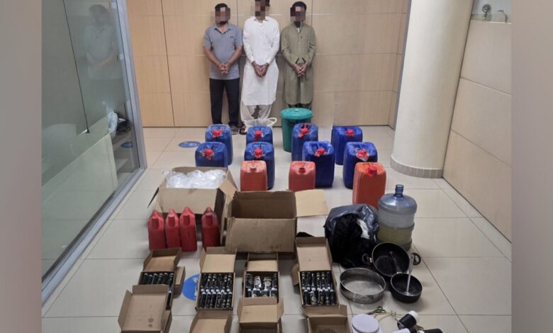 Boxes and containers of oil with seized narcotics displayed by Abu Dhabi Police alongside three arrested suspects.