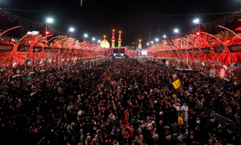 Crowds of Shiite worshippers gather in Karbala, Iraq, during the Arbaeen pilgrimage at night, with illuminated shrines in the background.