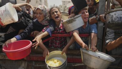 Displaced people in Gaza reach out with pots and containers during food distribution amid shortages.
