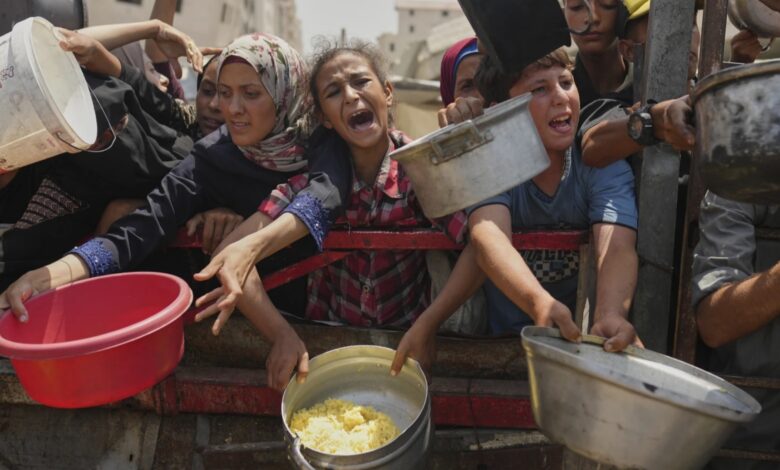 Displaced people in Gaza reach out with pots and containers during food distribution amid shortages.