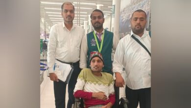 Indian expat in wheelchair at Saudi airport with embassy officials before flying home.