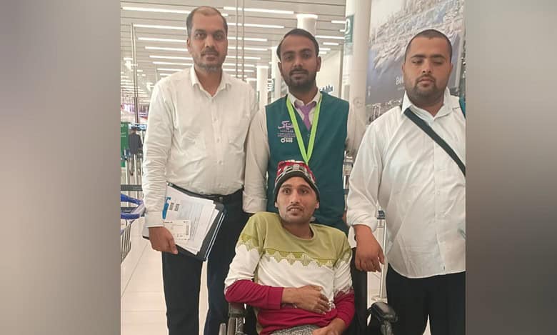 Indian expat in wheelchair at Saudi airport with embassy officials before flying home.