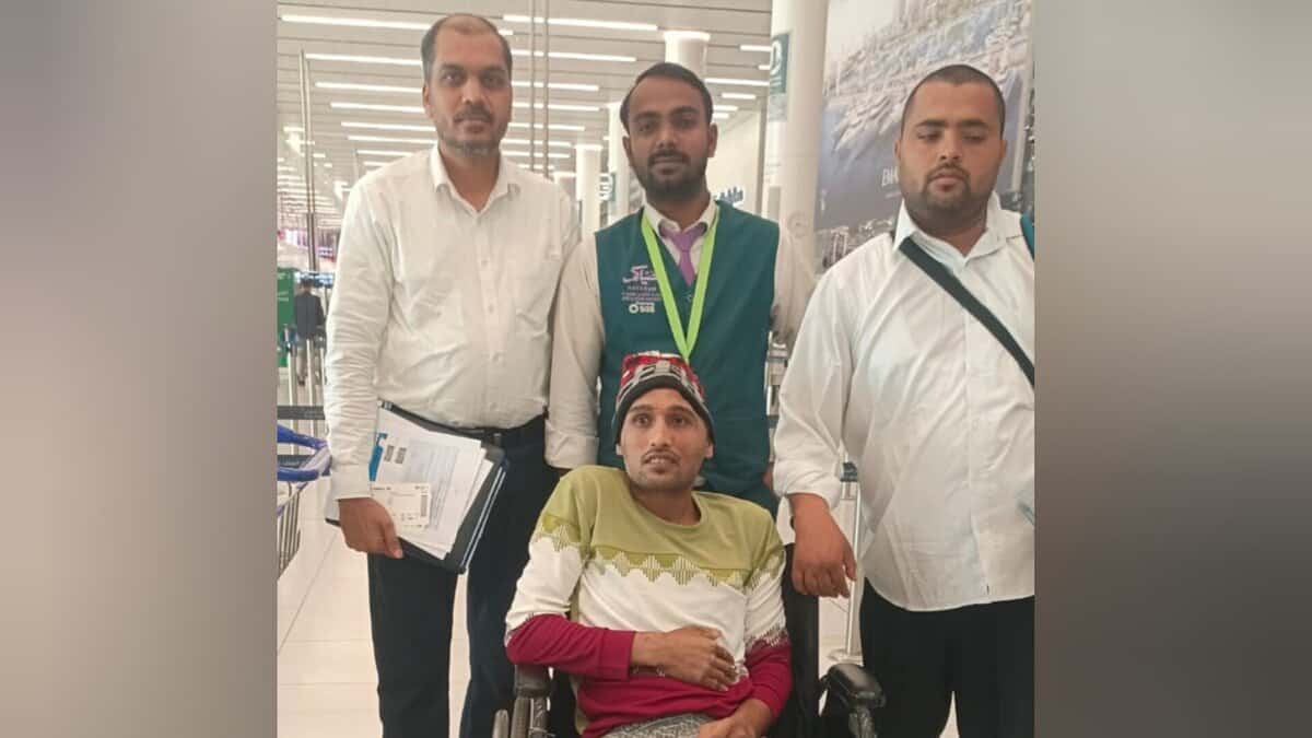 Indian expat in wheelchair at Saudi airport with embassy officials before flying home.