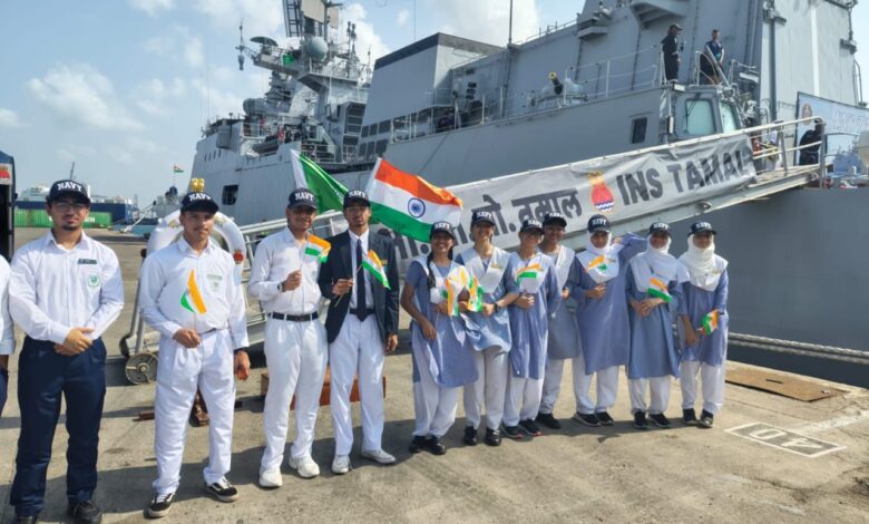 A group of Indian school students and Navy personnel holding Indian flags stand in front of INS Tamal during its port call in Jeddah, Saudi Arabia.