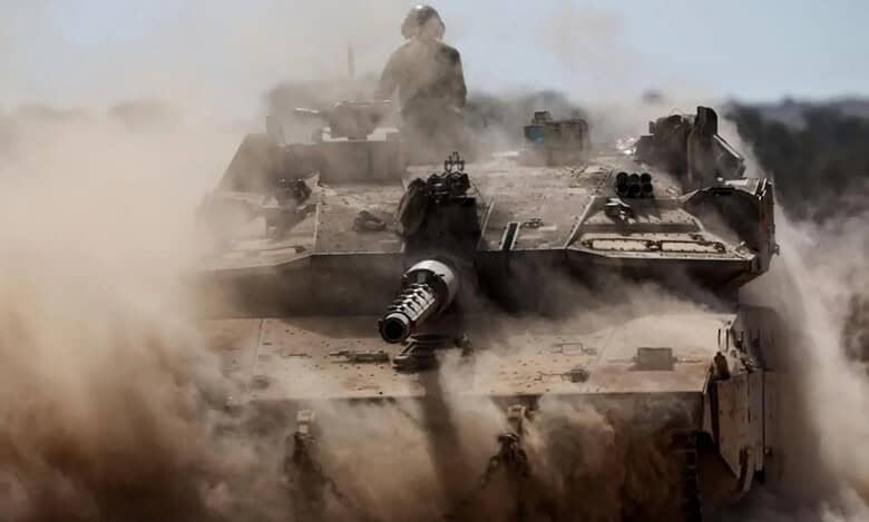 Israeli tank advancing through dust during Gaza ground offensive.