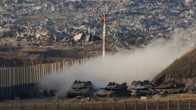 Israeli tanks manoeuvre near the Gaza border with destroyed buildings visible in the background, August 27, 2025.