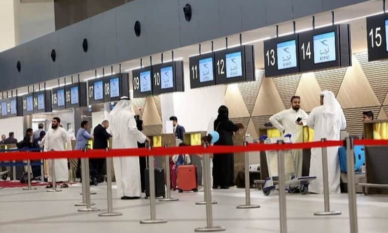 Passengers queue at check-in counters inside Kuwait International Airport.
