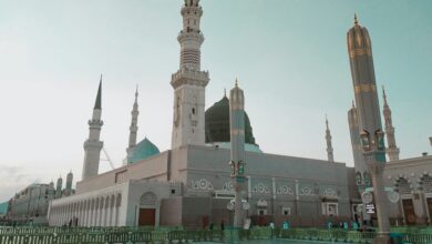 A view of the Prophet’s Mosque in Madinah, Saudi Arabia, with its iconic green dome and minarets under a clear sky.