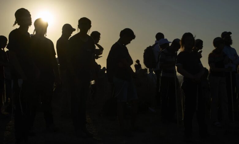 Silhouettes of Orthodox Jewish men standing together at sunset near the Gaza border.