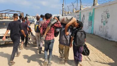 Palestinians carry wounded man near Gaza aid distribution point amid conflict.