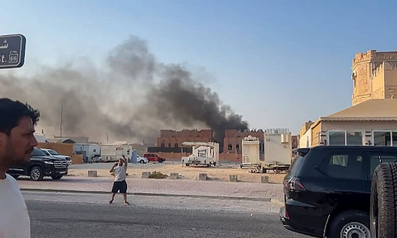 Smoke billows into the sky behind buildings in central Doha as people look on, following explosions in the Qatari capital on 9 September 2025.