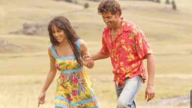 A couple joyfully walks hand-in-hand through a golden field, smiling and enjoying the sunny day.