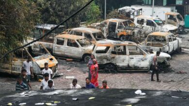 People walk past vandalized vehicles in the aftermath of anti-government protests