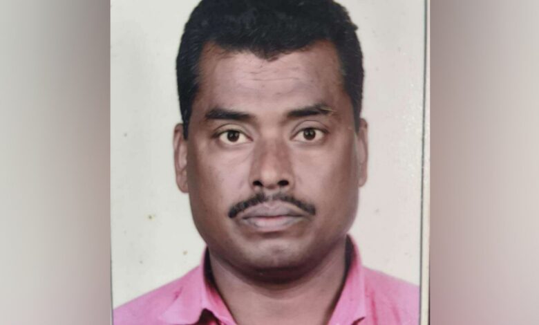 A passport-style photograph of Mohammad Rafi, a 50-year-old Indian man from Telangana with short black hair, a thin mustache, and a serious expression, wearing a pink collared shirt against a plain gray background.
