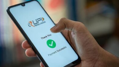 A person holding a smartphone displaying a successful UPI payment confirmation screen. The screen shows the UPI logo, a green checkmark, and the text "Thank You" and "Payment Successful" in English.