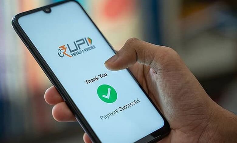A person holding a smartphone displaying a successful UPI payment confirmation screen. The screen shows the UPI logo, a green checkmark, and the text "Thank You" and "Payment Successful" in English.