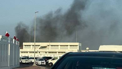 Thick black smoke billows behind buildings in Doha, Qatar, after multiple explosions.