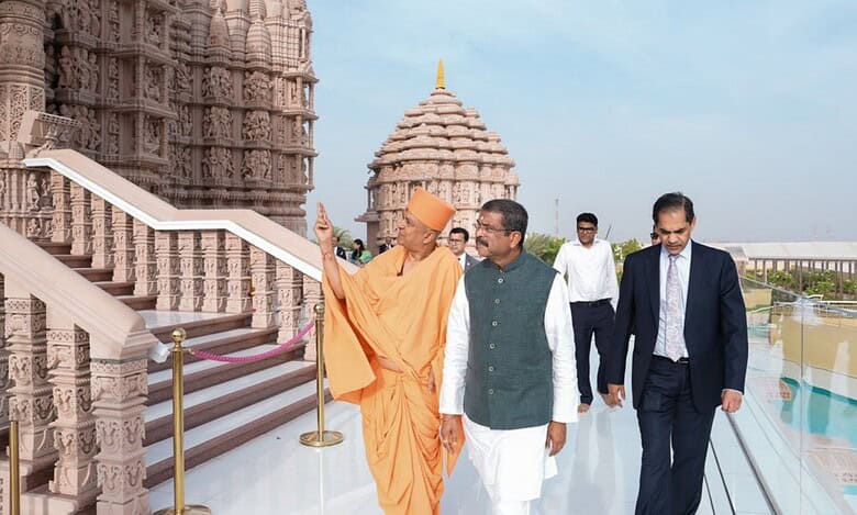 Union Minister Dharmendra Pradhan visits the intricately carved BAPS Hindu temple in Abu Dhabi, guided by a BAPS swami, with other officials walking alongside.