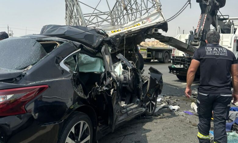 Damaged black car after accident with rescue team on highway, emergency response scene.