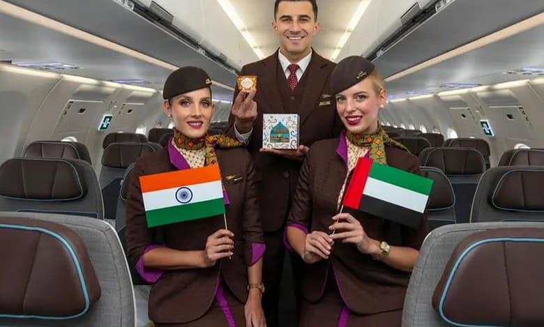 Etihad Airways cabin crew pose inside an aircraft holding Indian and UAE flags, celebrating the new Abu Dhabi–Kolkata A321LR service.