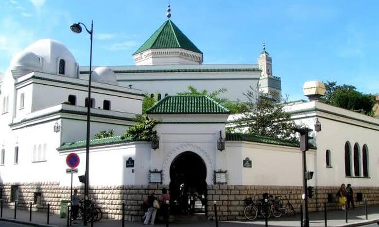 The Grand Mosque of Paris with its white walls, green-tiled roof and traditional Islamic architecture on a bright day.