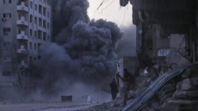 Palestinians take cover amid rubble as thick smoke rises from a building hit by an Israeli airstrike in Gaza City, September 7, 2025.