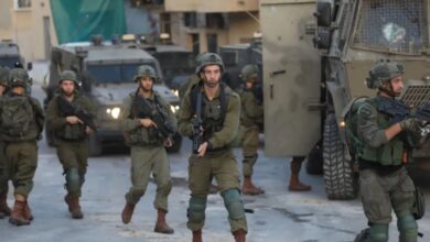 Israeli soldiers patrol near armoured vehicles at a West Bank checkpoint.