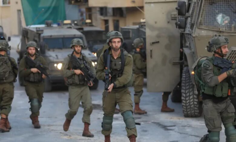 Israeli soldiers patrol near armoured vehicles at a West Bank checkpoint.