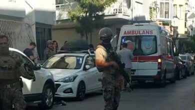 Turkish special forces guard a street in Izmir after a police station attack, with an ambulance in the background.