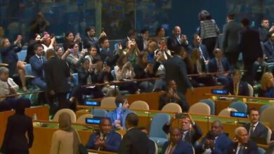 Delegates leaving the UN General Assembly hall as others clap during a session.