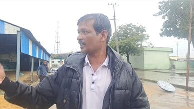 The image shows a farmer showing how paddy got washed away in the rain at Mothkur agricultural market yard on Monday, October 13, 2025.