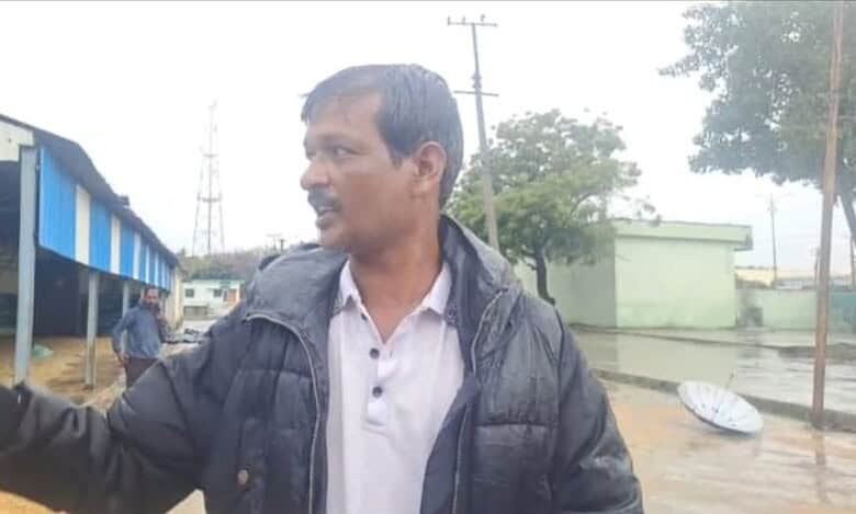 The image shows a farmer showing how paddy got washed away in the rain at Mothkur agricultural market yard on Monday, October 13, 2025.