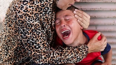 A Palestinian woman comforts a child as casualties are brought into Al-Aqsa Martyrs Hospital following an Israeli strike in Deir el-Balah, central Gaza Strip, on July 10, 2025 [File: Ramadan Abed/Reuters]