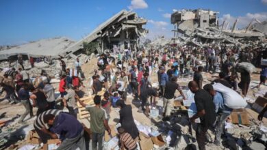 Palestinians receive food parcels after aid trucks entered from the Karem Abu Salem crossing, in Khan Younis, southern Gaza Strip [AFP]