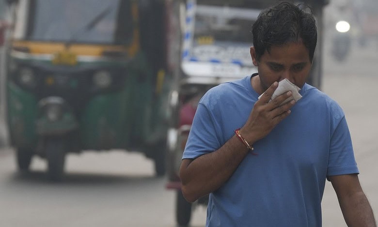 A commuter covers his face while making his way amid low visibility as air quality deteriorates across Delhi-NCR, in New Delhi, Tuesday, Oct. 21, 2025. (PTI Photo/Shahbaz Khan)