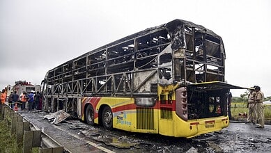 Police personnel investigate the spot where a Bengaluru-bound private bus caught fire after colliding with a two-wheeler, with the blaze being triggered after the motor bike with its fuel cap open was dragged underneath the bus, in Kurnool district on Friday. At least 20 people were killed in the accident. (PTI Photo)
