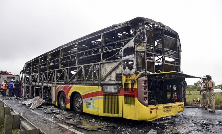Police personnel investigate the spot where a Bengaluru-bound private bus caught fire after colliding with a two-wheeler, with the blaze being triggered after the motor bike with its fuel cap open was dragged underneath the bus, in Kurnool district on Friday. At least 20 people were killed in the accident. (PTI Photo)