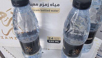 Three 330-ml bottles of Zamzam water placed on a box labelled “Zamzam bottled water, 24 bottles, 330 ml.”