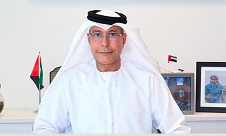 Emirati businessman and former diplomat Hamad bin Ahmed bin Salem Al Hajri seated at his desk with UAE flags and framed photo behind.